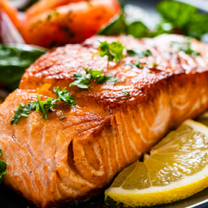 Cooked salmon on a plate with a lemon wedge